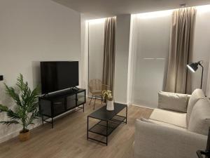 uma sala de estar com um sofá e uma televisão de ecrã plano em Demetrio By Alma Suites em Valência