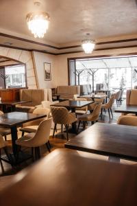 ein Restaurant mit Tischen, Stühlen und Fenstern in der Unterkunft Marmaros Apart-Hotel & Spa in Bukowel