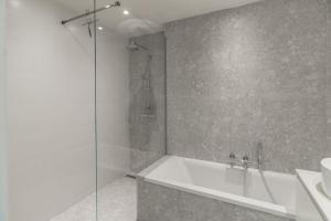 y baño con ducha, bañera y lavamanos. en Classy flat with awesome view and great location! en Amberes