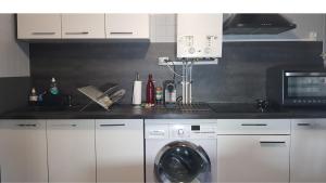 a kitchen with a washing machine and a microwave at Vue sur la Bastille - Appt Calme et Cosy-Netflix-Fibre in Grenoble