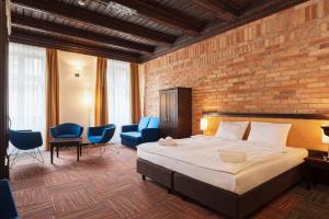 a bedroom with a bed and chairs and a brick wall at Palazzo Rosso Old Town in Poznań