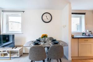 a dining room table with chairs and a clock on the wall at Live the Wembley Buzz! Stylish Flat near Station & Amenities in London
