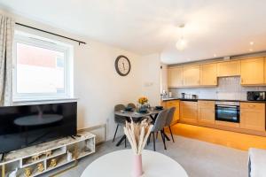 a kitchen with a table and a clock on the wall at Live the Wembley Buzz! Stylish Flat near Station & Amenities in London