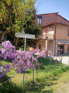 un cartel frente a una casa con flores púrpuras en Agriturismo Osea, en Monteriggioni