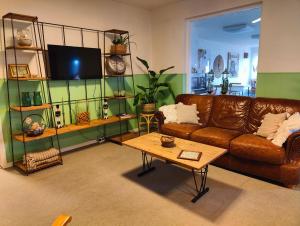 a living room with a brown couch and a coffee table at Pension Skovly in Tranekær
