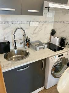 a kitchen with a sink and a washing machine at Exclusive Private Apartment by Warilco - Pleyel 25 m2 - À 1 minute de la station métro Carrefour Pleyel in Saint-Denis