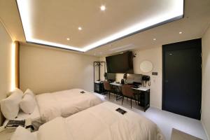 ein Hotelzimmer mit 2 Betten und einem Schreibtisch in der Unterkunft Hotel141 in Daejeon