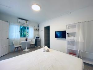 um quarto com uma grande cama branca e uma mesa em SLAV Naithon Boutique Hotel and Restaurant em Phuket