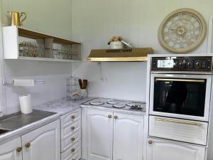 a white kitchen with a stove and a microwave at Water view retreat sanctuary in Koolewong