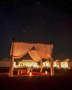 a tent in the middle of the desert at night at Merzouga Stars Luxury Camp in Merzouga
