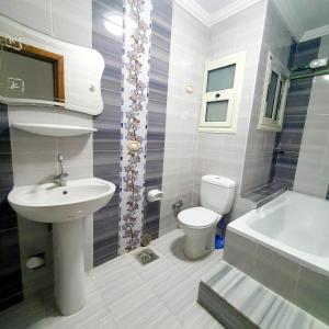 a bathroom with a sink and a toilet and a tub at Sea and Montaza Palace view 2 bedrooms apartment alexandria,2 full bathrooms, with 2 AC and 1 Stand Fan, wifi, 4 blankets available in Alexandria