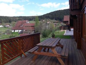 a wooden bench sitting on the deck of a house at Chalet Airelles 4 pers - Tout Confort - Wifi fibre in Xonrupt-Longemer