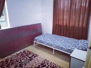 Dormitorio pequeño con cama y alfombra en D Landai Budget Room Family, en Pekan