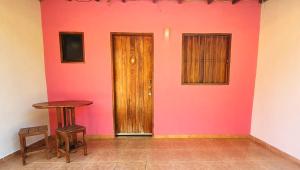 Habitación con pared de color rosa y puerta de madera. en Chalé da Vó en Vargem Bonita