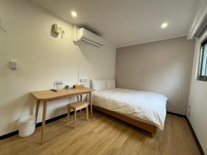 a small bedroom with a bed and a table at 宏洲旅社HZ Hotel in Taipei