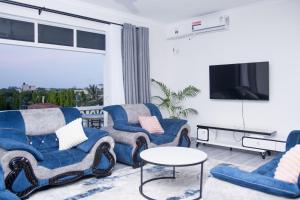 a living room with two blue chairs and a tv at Semo's Siloam apartments in Mombasa