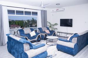 a living room with three blue chairs and a tv at Semo's Siloam apartments in Mombasa