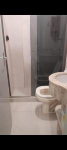 a bathroom with a toilet and a shower and a sink at Apartamento ótima localização in Torres