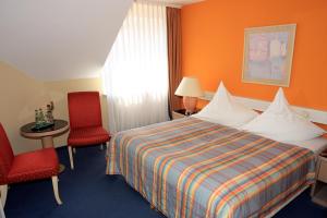 a hotel room with a bed and two red chairs at Ilmenauer Hof in Ilmenau