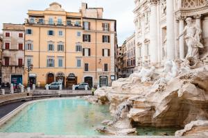 einen Brunnen in einer Stadt mit Gebäuden im Hintergrund in der Unterkunft Delfini Trevi House in Rom