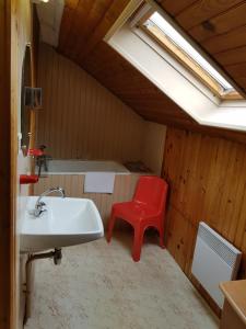 a bathroom with a sink and a red chair at Mamyvonne Vacances in Tendon