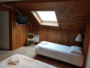 a bedroom with two beds and a tv and a skylight at Mamyvonne Vacances in Tendon