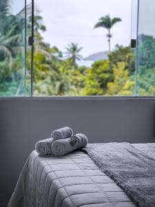 a bed with two towels on it in front of a window at Flats Apple Ilha com Banheira in Abraão