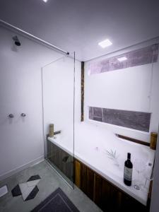 a bathroom with a glass shower with a bottle of wine at Flats do Pe na Areia in Abraão