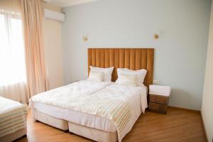 a bedroom with a large bed with a wooden headboard at Phazisi Hotel in Tbilisi City