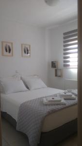 Un dormitorio blanco con una cama con toallas. en 7th Floor Stunning View Penthouse in Piraeus en Piraeus