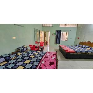 a room with two beds and a table and chairs at Hotel HillView, Junagadh in Junagadh
