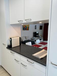 a kitchen with white cabinets and a living room at Steghorn in Leukerbad