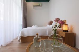 een slaapkamer met een bed en een tafel met een vaas met bloemen bij Lemi - Homestay in Hue in Hue