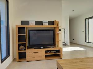 TV en un centro de entretenimiento de madera en una sala de estar en Villa neuve de standing au calme, en Sommières