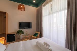 a bedroom with a white bed and a tv at Lemi - Homestay in Hue in Hue