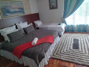 a hotel room with two beds and a rug at Comrades Oasis Guest House in Pietermaritzburg