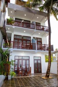 a building with a balcony with a table and chairs at Asa Bay Beach Resort in Talpe
