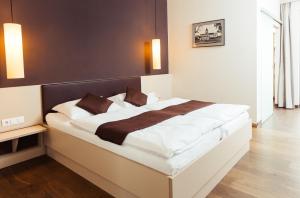 ein Schlafzimmer mit einem großen Bett mit weißer Bettwäsche und braunen Kissen in der Unterkunft WEINBLICK & WEINGUT Grafinger in Senftenberg
