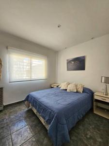 a bedroom with a blue bed and a window at OlaLasGrutas Casa 4ta Bajada in Las Grutas