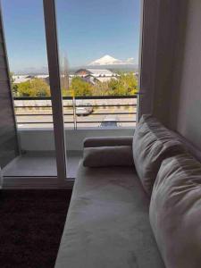 a couch in a room with a large window at Depto. con Vista al Volcan in Villarrica