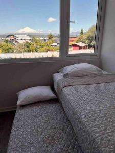 a bedroom with a bed and a large window at Depto. con Vista al Volcan in Villarrica +5 photos