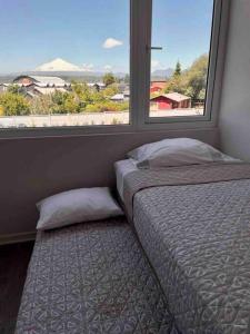 a bedroom with a bed and a large window at Depto. con Vista al Volcan in Villarrica