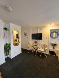 a living room with a table and chairs and a mirror at Deluxe Town Centre Studio Stevenage in Stevenage