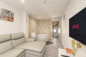 een woonkamer met een witte bank en een tv bij La Suite Neuvilloise in Neuville-sur-Saône