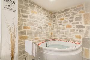 a bathroom with a bath tub with a stone wall at La Suite Neuvilloise in Neuville-sur-Saône