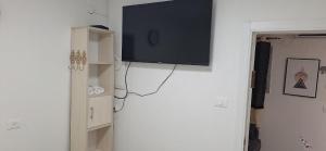 telewizor z płaskim ekranem wiszący na białej ścianie w obiekcie RutSuite w mieście Afula
