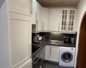 a kitchen with white cabinets and a washing machine at Haus Schmidhuber Wohnung 5 mit sonniger Terrasse in Grossgmain