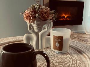 a cup of coffee and a vase with flowers next to a fireplace at Ski, cocoa & novel apartment Bjelašnica, garage & ski room in Bjelašnica