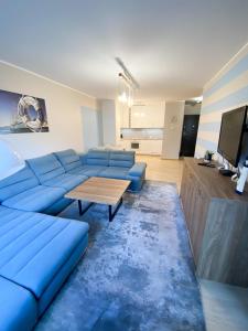 a living room with a blue couch and a tv at Apartament Blue Island in Kołobrzeg