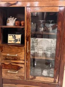 a wooden cabinet filled with glasses and dishes at Centrally located, big home in Kolkata